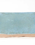 Closeup of a single pale aquamarine blue-green square ceramic tile.