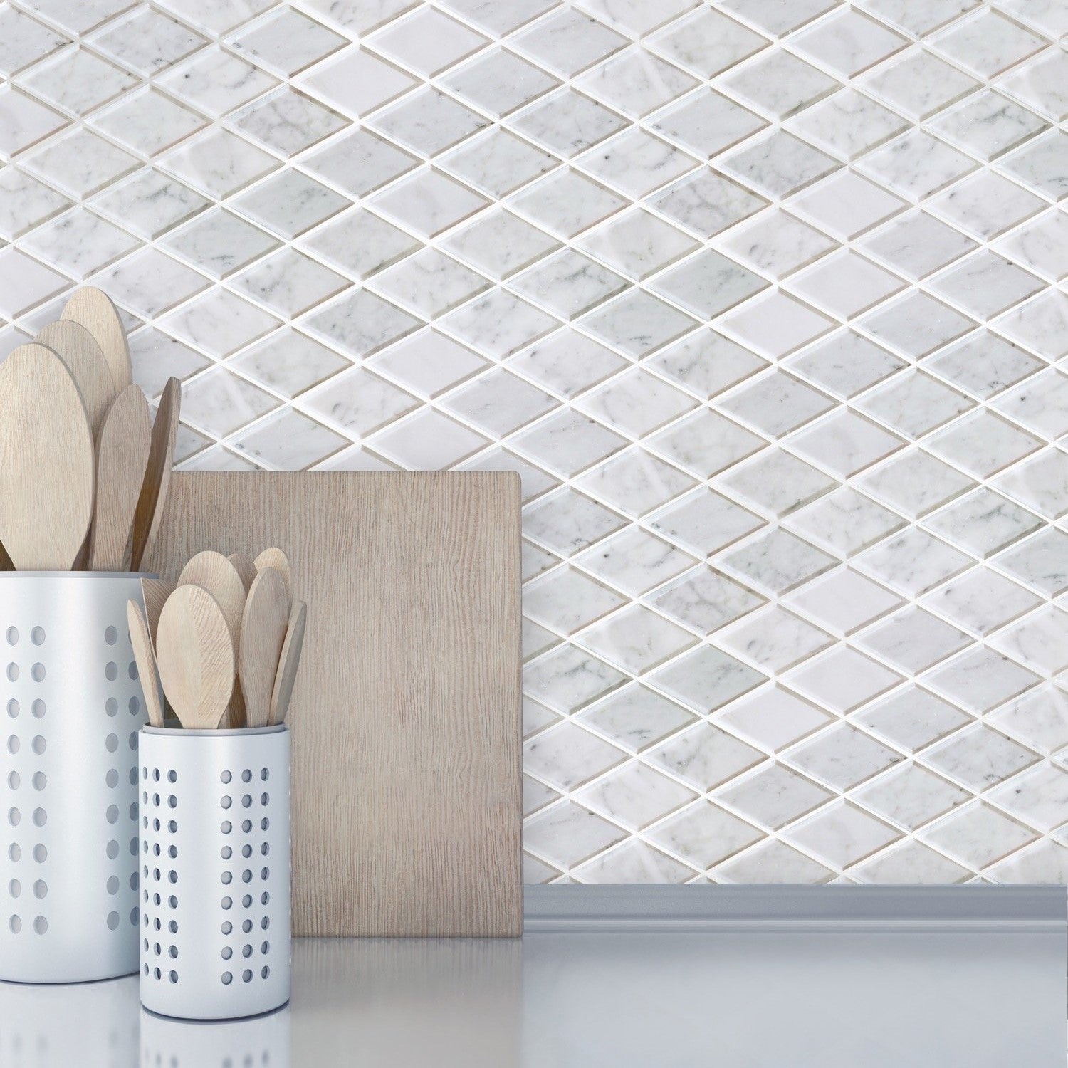 Kitchen countertop with wooden utensils, wood cutting board, and white and gray marble beveled diamond tile backsplash.