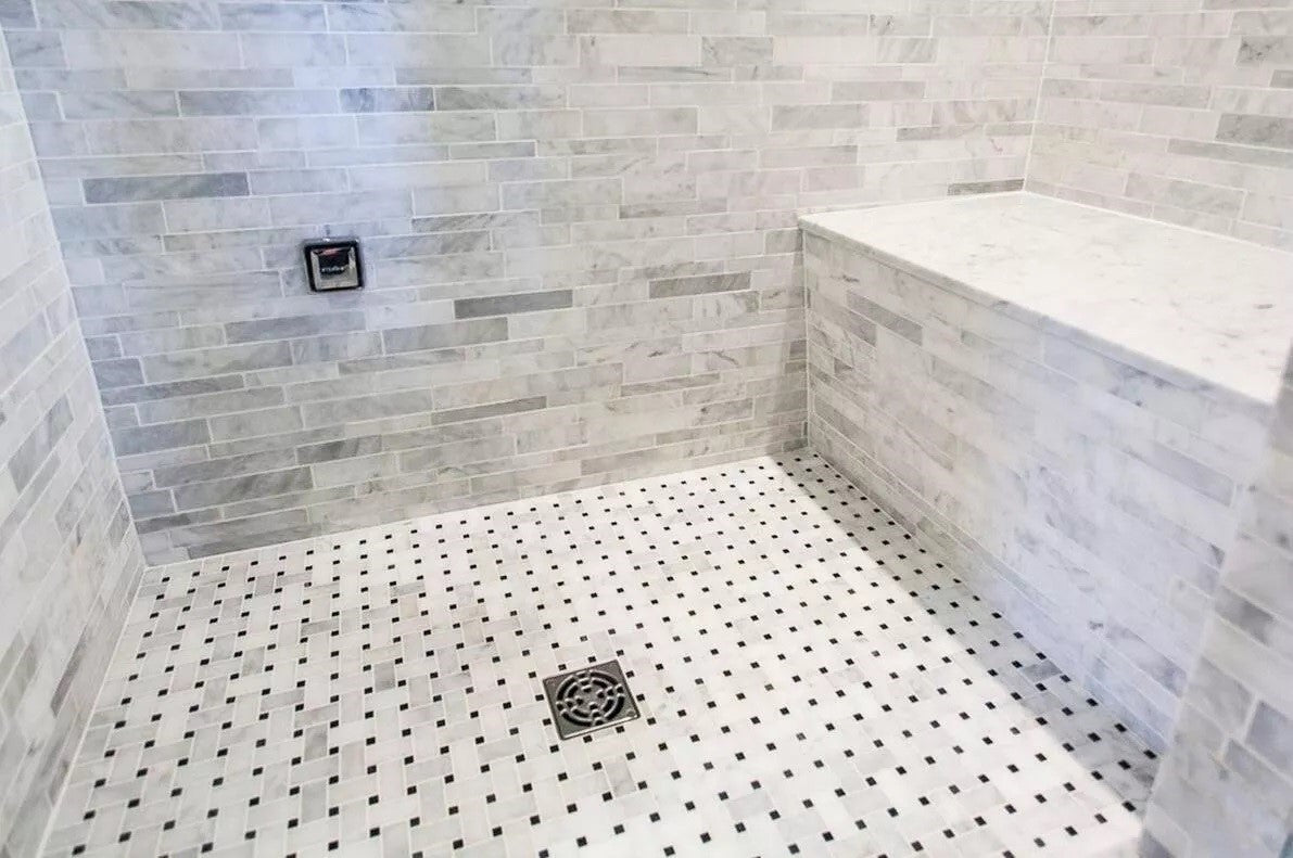Closeup of a Calacatta Marble Walk-In Shower with Built-In Shower Bench and Basketweave Tile Surrounding Square Floor Drain