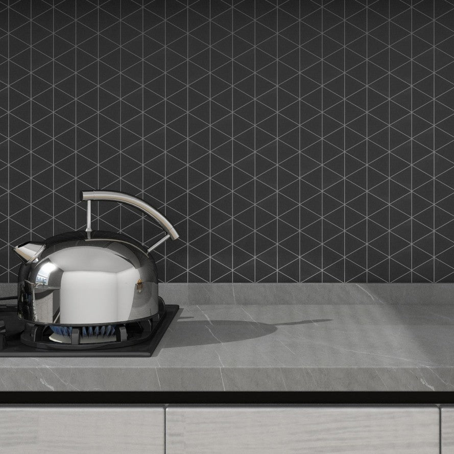 Gray Kitchen Countertop and Tea Kettle on Burner in Front of Matte Black Ceramic Triangle Mosaic Tile Backsplash