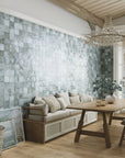 Modern rustic dining room featuring light color wood floors, wooden table, beige cushioned bench, and tiled accent wall in blue-green 4x4 ceramic tiles with  ample gray variation and fading.