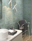 Bathroom with aqua blue distressed look ceramic subway tile walls, white vanity, modern industrial style light fixture, and standing towel rack